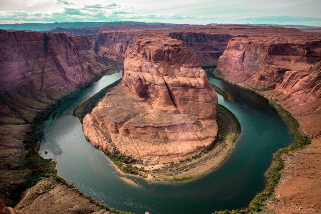 Aerial view of Horseshoe Bend, where the Colorado River curves around a massive sandstone formation in the Arizona desert.