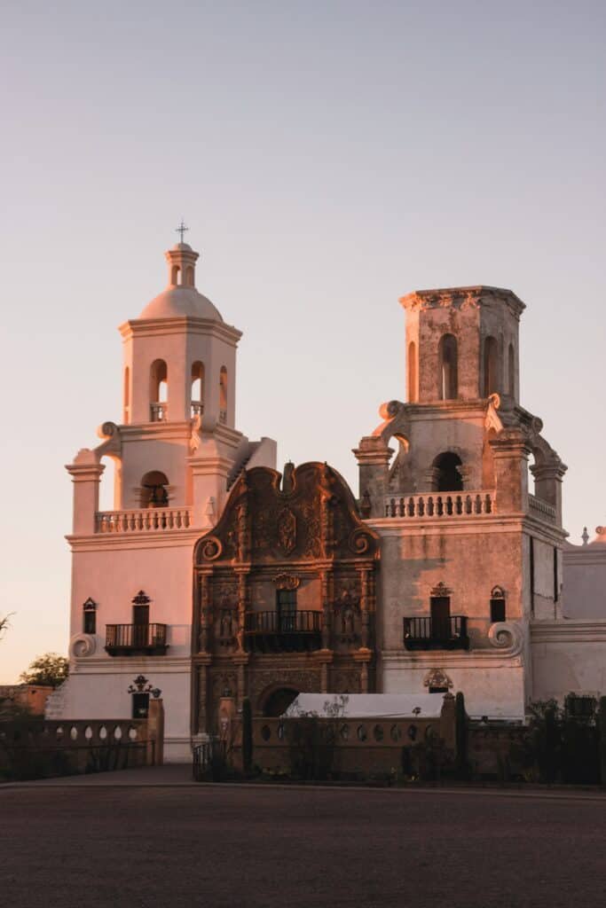 Historic Mission San Xavier del Bac, a Spanish colonial church in Arizona, bathed in warm sunset light.